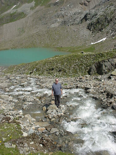 Plätschernder Gebirgsbach an grünem Alpensee.